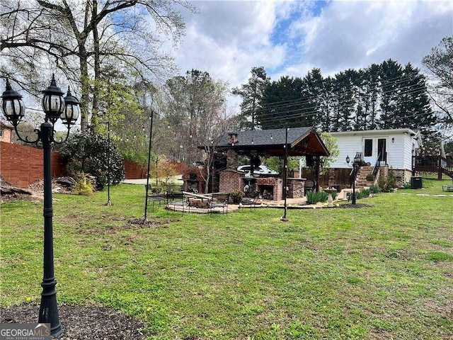 view of yard with an outdoor stone fireplace, fence, and central AC unit