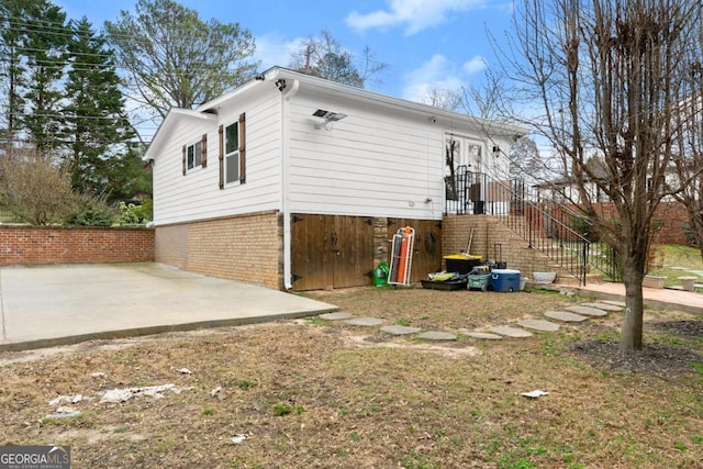 view of side of home with a patio area, stairs, and brick siding