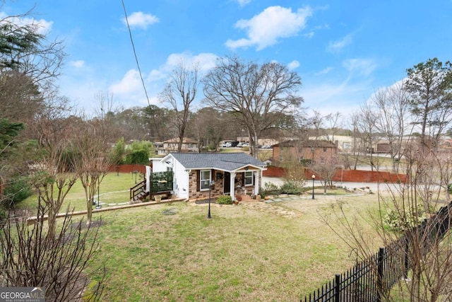 exterior space featuring stone siding, fence, and a front yard