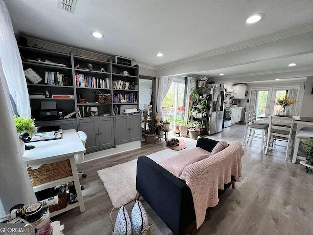 living area with ornamental molding, recessed lighting, visible vents, and light wood-style floors