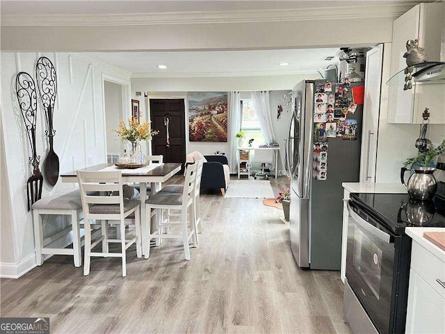 dining area with ornamental molding and light wood-style flooring