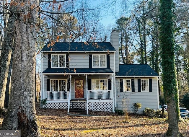 traditional home featuring covered porch and a chimney