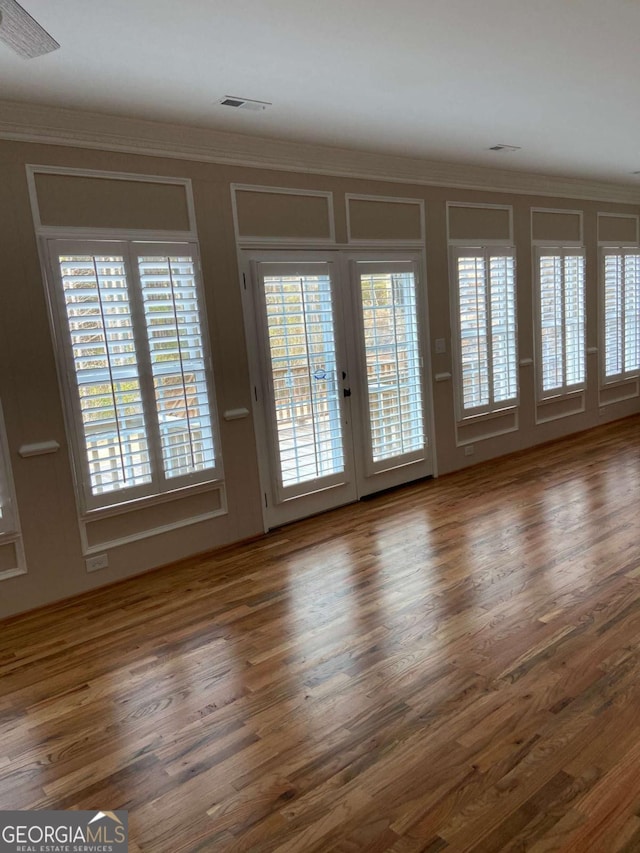 interior space with wood finished floors, visible vents, and crown molding