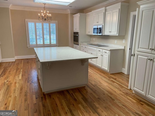 kitchen with ornamental molding, appliances with stainless steel finishes, light wood finished floors, and white cabinets