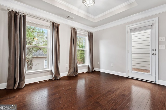 empty room with dark wood-type flooring, a tray ceiling, plenty of natural light, and ornamental molding