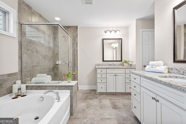 full bathroom with two vanities, a sink, a shower stall, and a bath