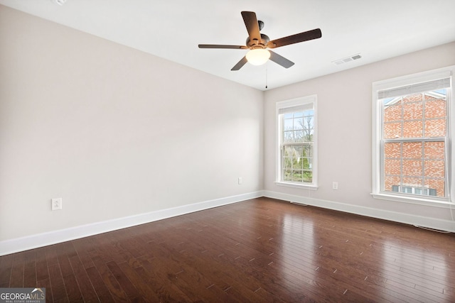 empty room with ceiling fan, visible vents, baseboards, and dark wood finished floors