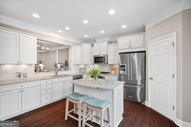 kitchen with appliances with stainless steel finishes, crown molding, a sink, and white cabinetry