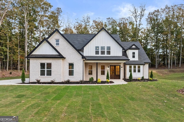 modern inspired farmhouse with brick siding, a front lawn, and roof with shingles