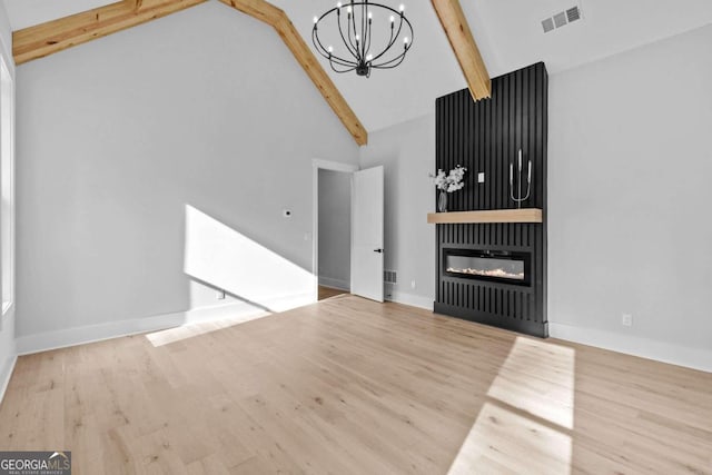 unfurnished living room with high vaulted ceiling, a notable chandelier, visible vents, beam ceiling, and a glass covered fireplace