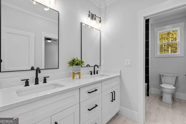 full bath featuring double vanity, crown molding, a sink, and wood finished floors