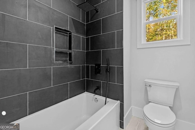 bathroom with shower / bathtub combination, toilet, and baseboards