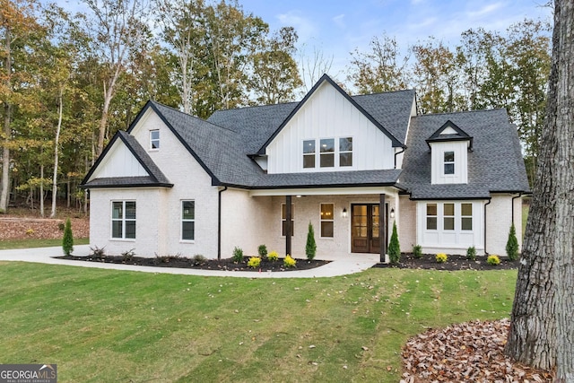 modern inspired farmhouse with a shingled roof, brick siding, french doors, a front lawn, and board and batten siding