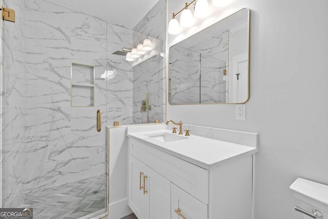 bathroom featuring toilet, a marble finish shower, and vanity