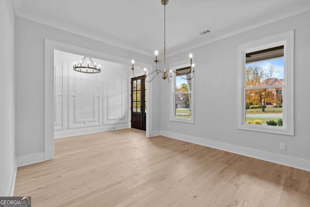 unfurnished dining area featuring light wood-style floors, a wealth of natural light, and a notable chandelier