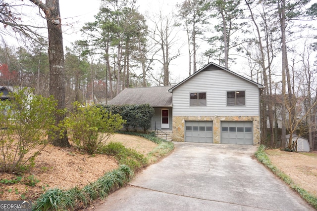 split level home featuring an attached garage, stone siding, driveway, and a shingled roof