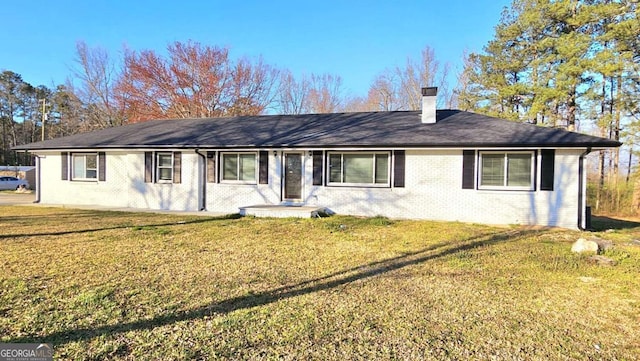 single story home with brick siding, a chimney, and a front yard