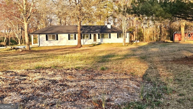 ranch-style home with a chimney and a front yard