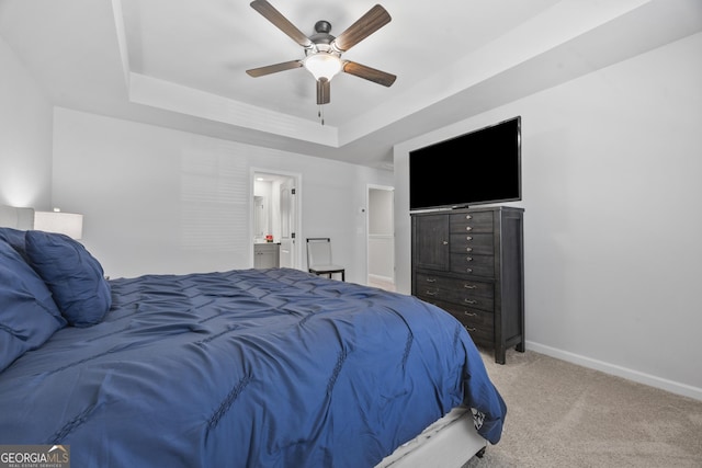 bedroom featuring ceiling fan, connected bathroom, light colored carpet, baseboards, and a raised ceiling