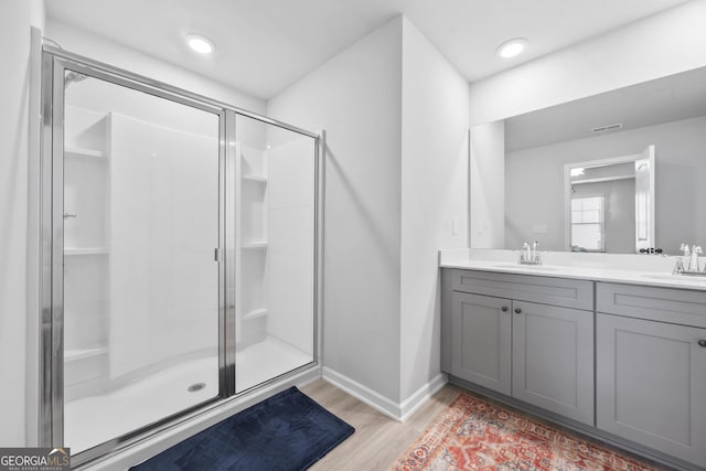 bathroom with wood finished floors, a stall shower, and a sink