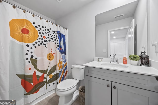 bathroom featuring toilet, a shower with shower curtain, wood finished floors, vanity, and visible vents