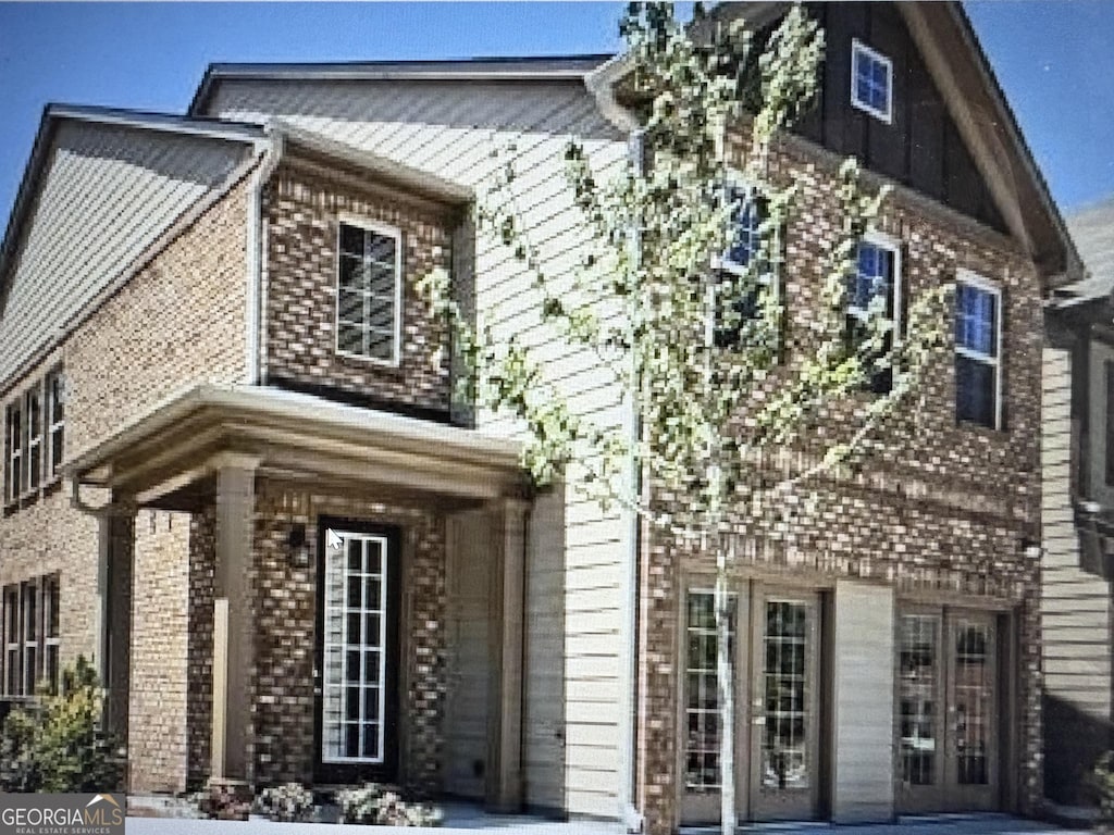 view of front of property featuring french doors, brick siding, and a patio