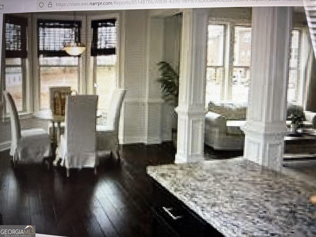 dining space featuring decorative columns and wood finished floors