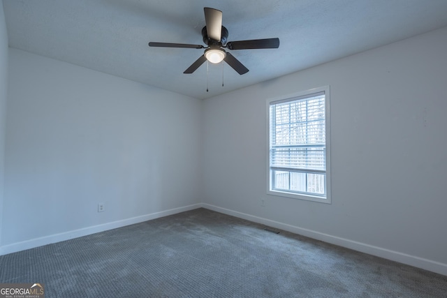 carpeted empty room with visible vents, baseboards, and a ceiling fan