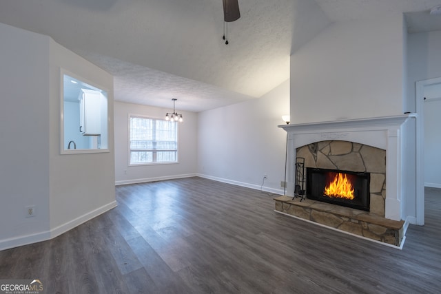 unfurnished living room with a textured ceiling, ceiling fan with notable chandelier, a fireplace, wood finished floors, and baseboards