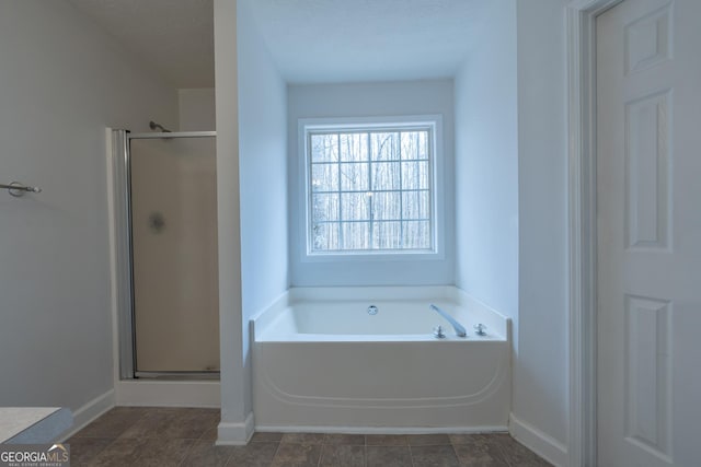 full bathroom featuring a stall shower, baseboards, and a bath