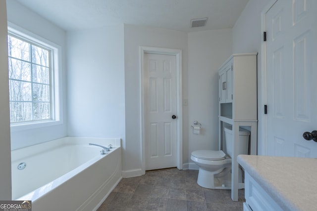 full bath with visible vents, toilet, vanity, baseboards, and a bath