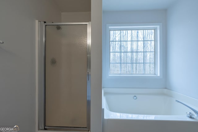 bathroom featuring a garden tub and a shower stall