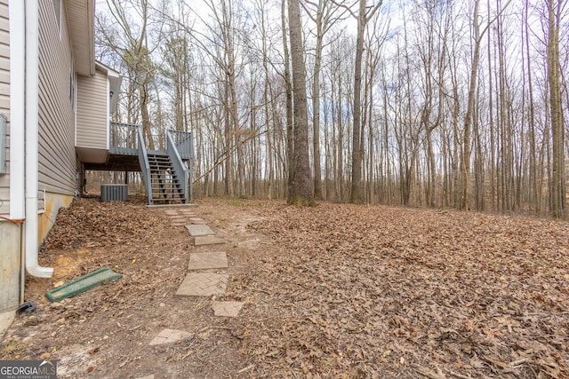 view of yard featuring a deck, central AC unit, and stairs