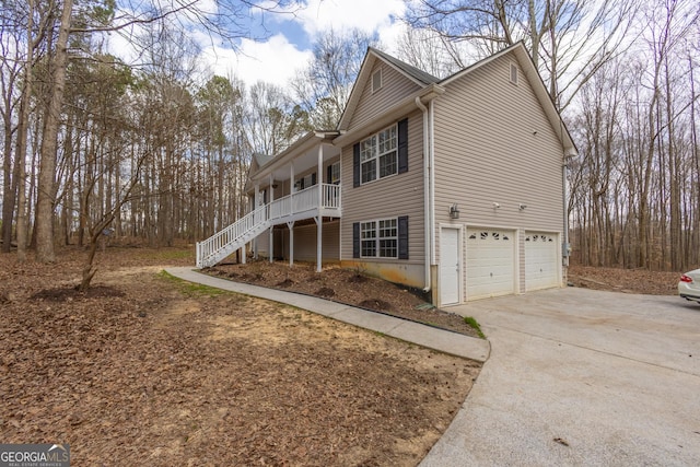 view of side of home with an attached garage, stairway, and concrete driveway