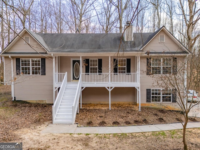 view of front of home with covered porch, stairway, and a chimney