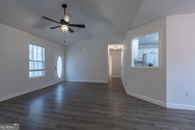 unfurnished living room featuring dark wood-type flooring, lofted ceiling, ceiling fan, and baseboards