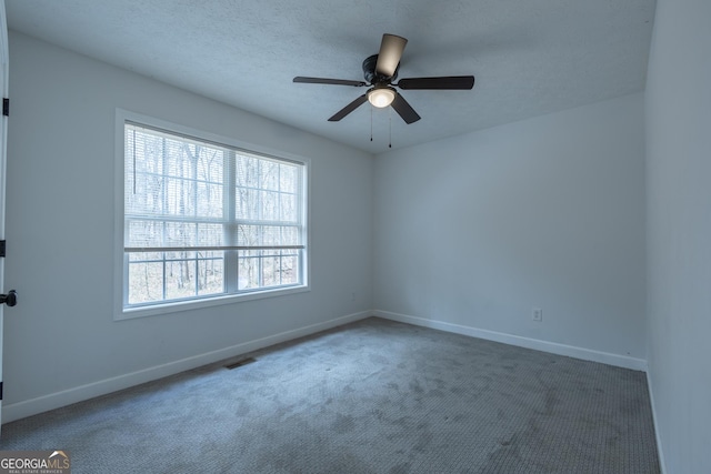 spare room with a ceiling fan, carpet, a textured ceiling, and baseboards