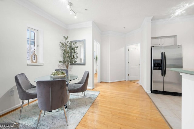 dining room with baseboards, crown molding, and light wood finished floors