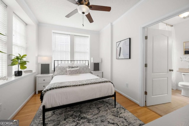 bedroom with baseboards, connected bathroom, ceiling fan, crown molding, and light wood-style floors