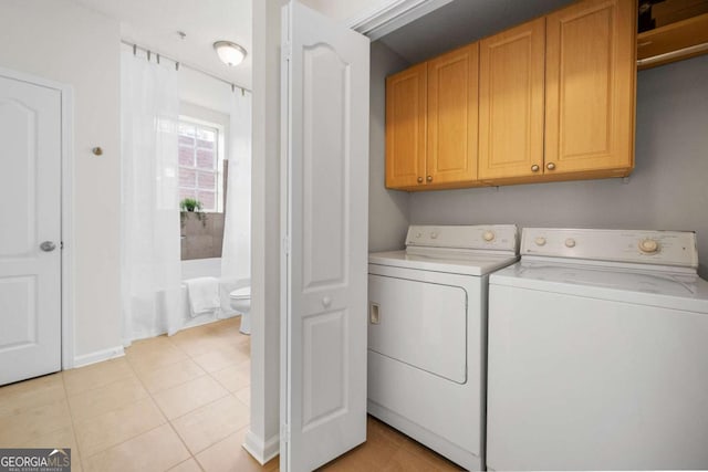 laundry area featuring light tile patterned floors, washer and clothes dryer, and cabinet space