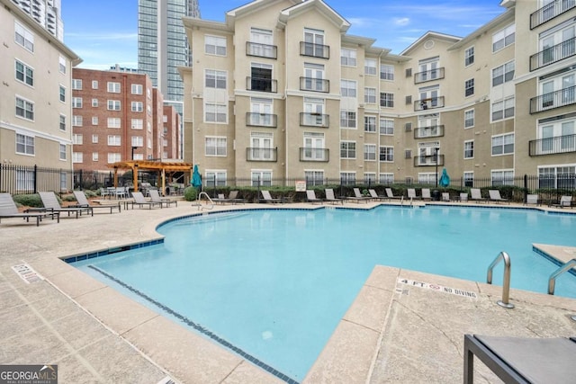 community pool with a patio area, fence, and a pergola