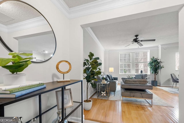 living room with a textured ceiling, wood finished floors, a ceiling fan, and crown molding