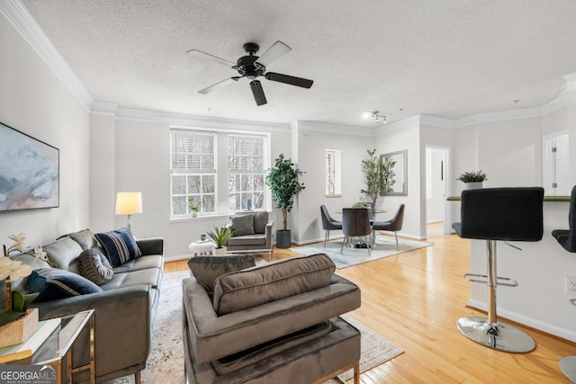 living room with a textured ceiling, ceiling fan, wood finished floors, and crown molding