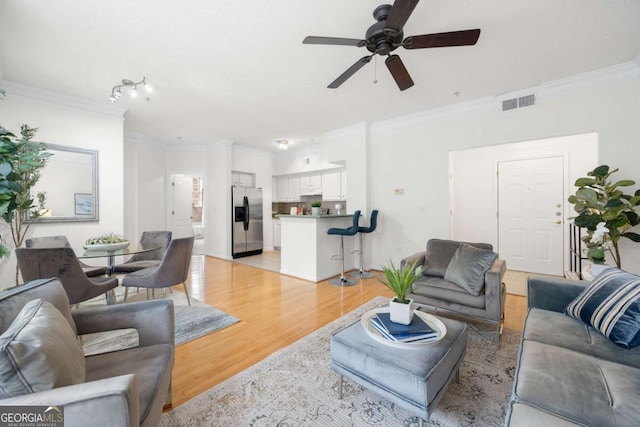 living area featuring ornamental molding, a ceiling fan, visible vents, and light wood-style floors