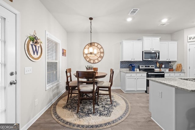 kitchen featuring stainless steel appliances, visible vents, backsplash, light wood-style floors, and white cabinets