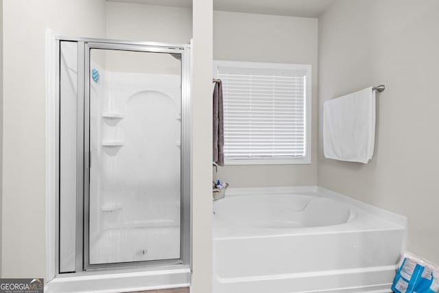 bathroom featuring a garden tub and a shower stall