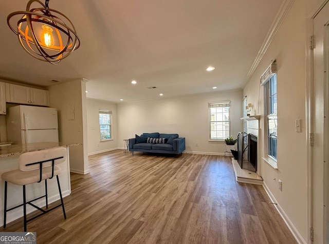 living room featuring recessed lighting, a fireplace with raised hearth, baseboards, and wood finished floors