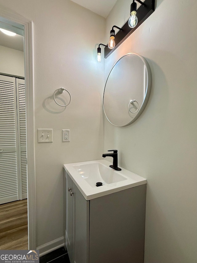 bathroom with baseboards, wood finished floors, and vanity