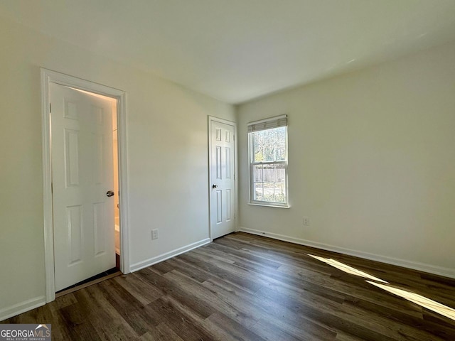 unfurnished bedroom with dark wood-type flooring and baseboards