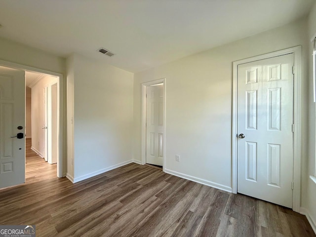 unfurnished bedroom featuring visible vents, baseboards, and wood finished floors